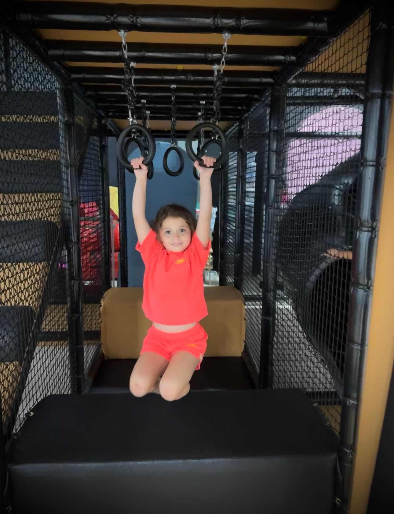 A child on the hanging rings in the climbing gym